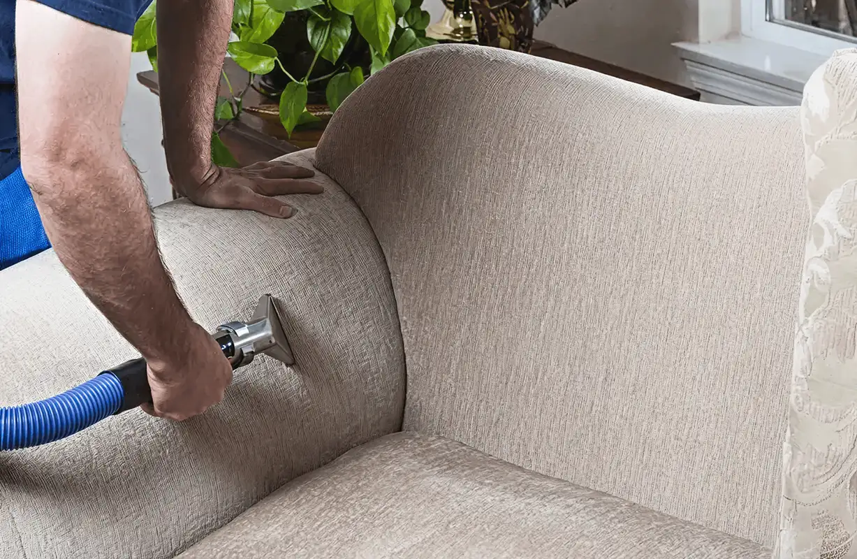 Professional upholstery cleaner deep-cleaning a fabric sofa with a handheld extraction tool and hose, San Diego, CA.